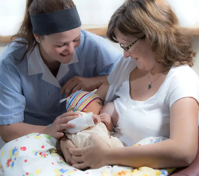 Hebamme unterstützt Mutter und ihr Baby beim Stillen